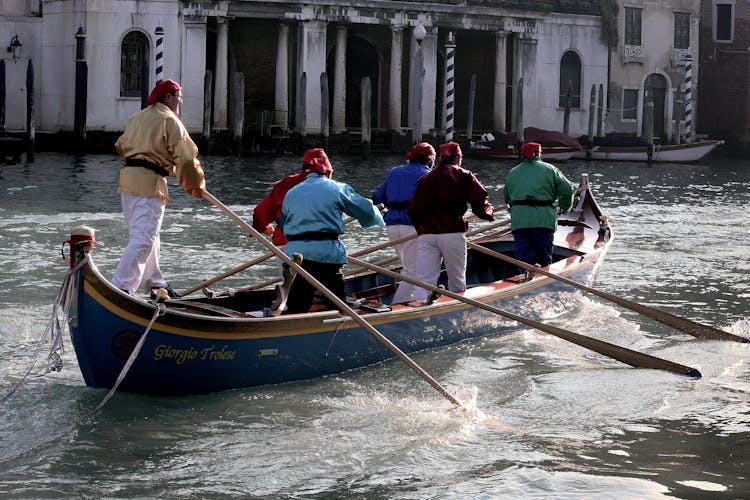 Men Rowing A Boat On Water Canal