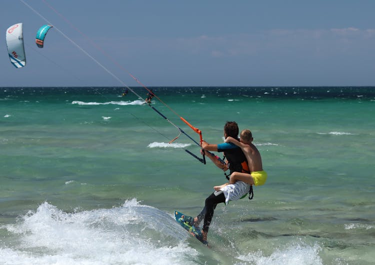 A Man And A Boy Enjoys Kitesurfing