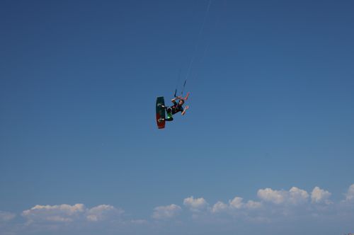 Free A kiteboarder performs an aerial stunt against a clear blue sky, epitomizing adventure and freedom. Stock Photo