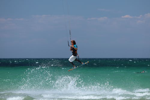 A Man in Blue and Black Wet Suit Surfing on Sea Waves