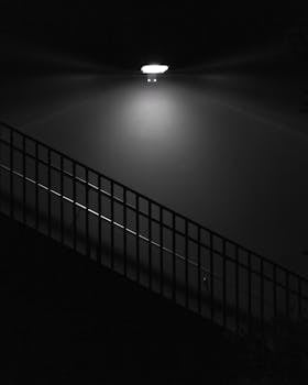 A dramatic black and white image of a stairwell illuminated by a single light source.