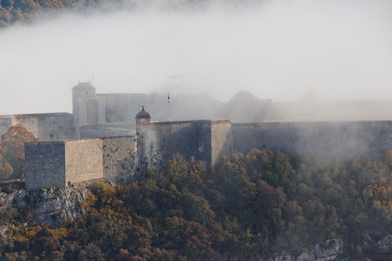 Fortezza di pietra avvolta dalla nebbia sopra la foresta — le Terre in Cenere