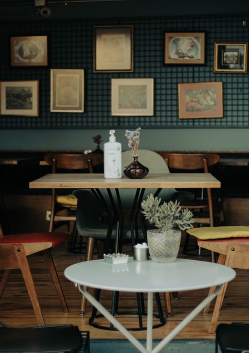 Free Inviting café interior featuring wooden tables, chairs, and artistic wall frames. Stock Photo
