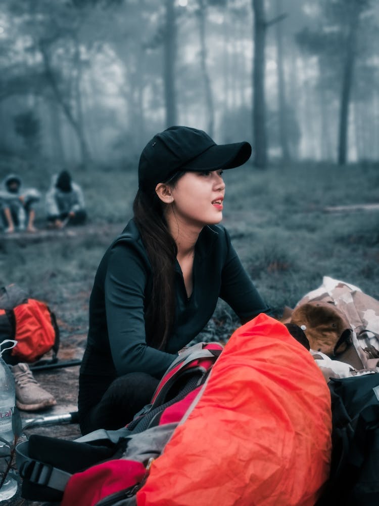 Woman In Cap Sitting On Camping In Forest