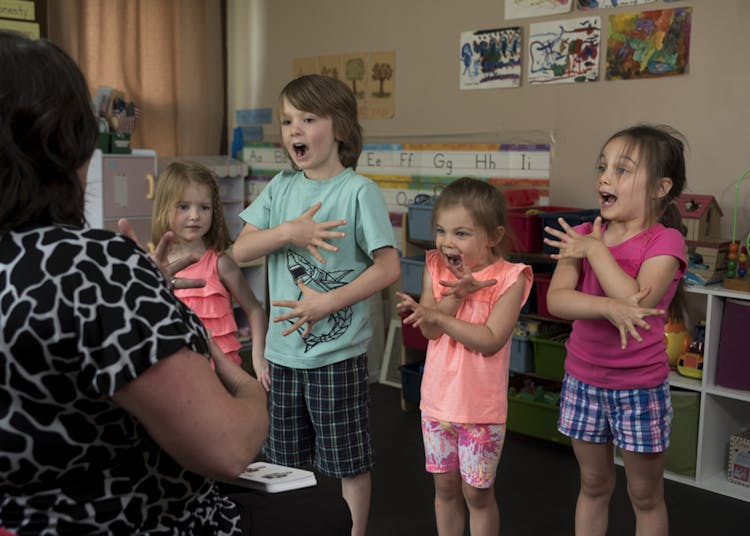 Kindergarten Kids Performing In Front Of A Teacher Inside Classroom