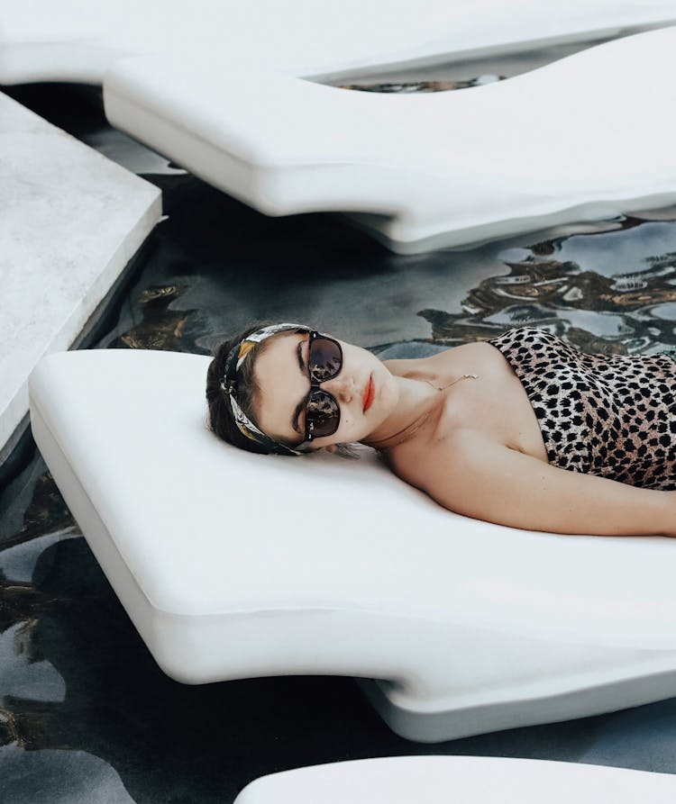 Woman In A Cheetah Print Swimming Costume Lying On A Floating In Water Sunbed