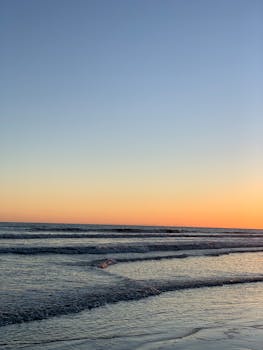 Serene view of ocean waves gently crashing on the shore during a breathtaking sunset.