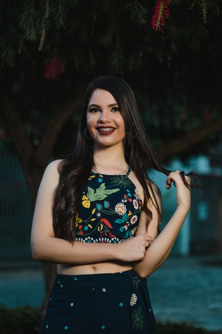 Portrait of a smiling woman in a floral dress outdoors, exuding confidence and style.