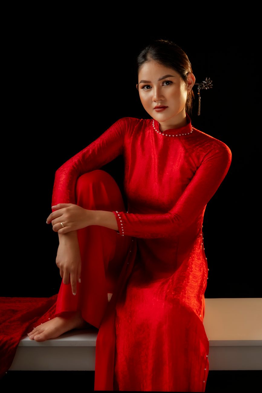 Portrait of a young Asian woman in traditional Ao Dai dress, posing gracefully in a studio.