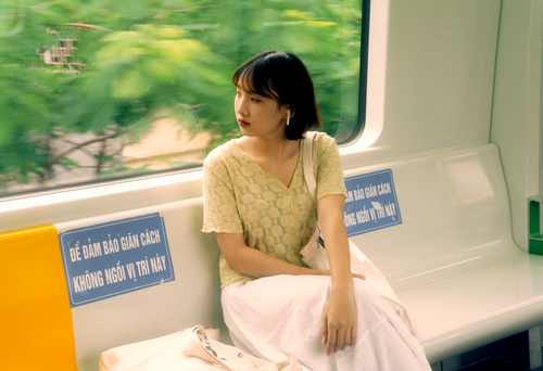Free A thoughtful young woman rides alone in an urban train, gazing out the window. Stock Photo