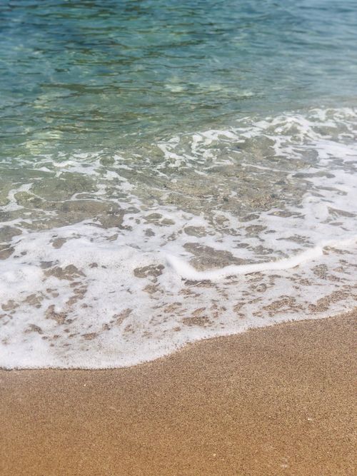 Free Peaceful beach scene with gentle waves lapping on sandy shore. Ideal for relaxation themes. Stock Photo