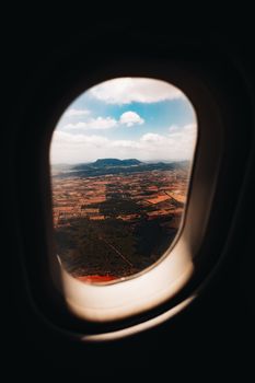 A picturesque landscape view through an airplane window, capturing the vast fields and sky.