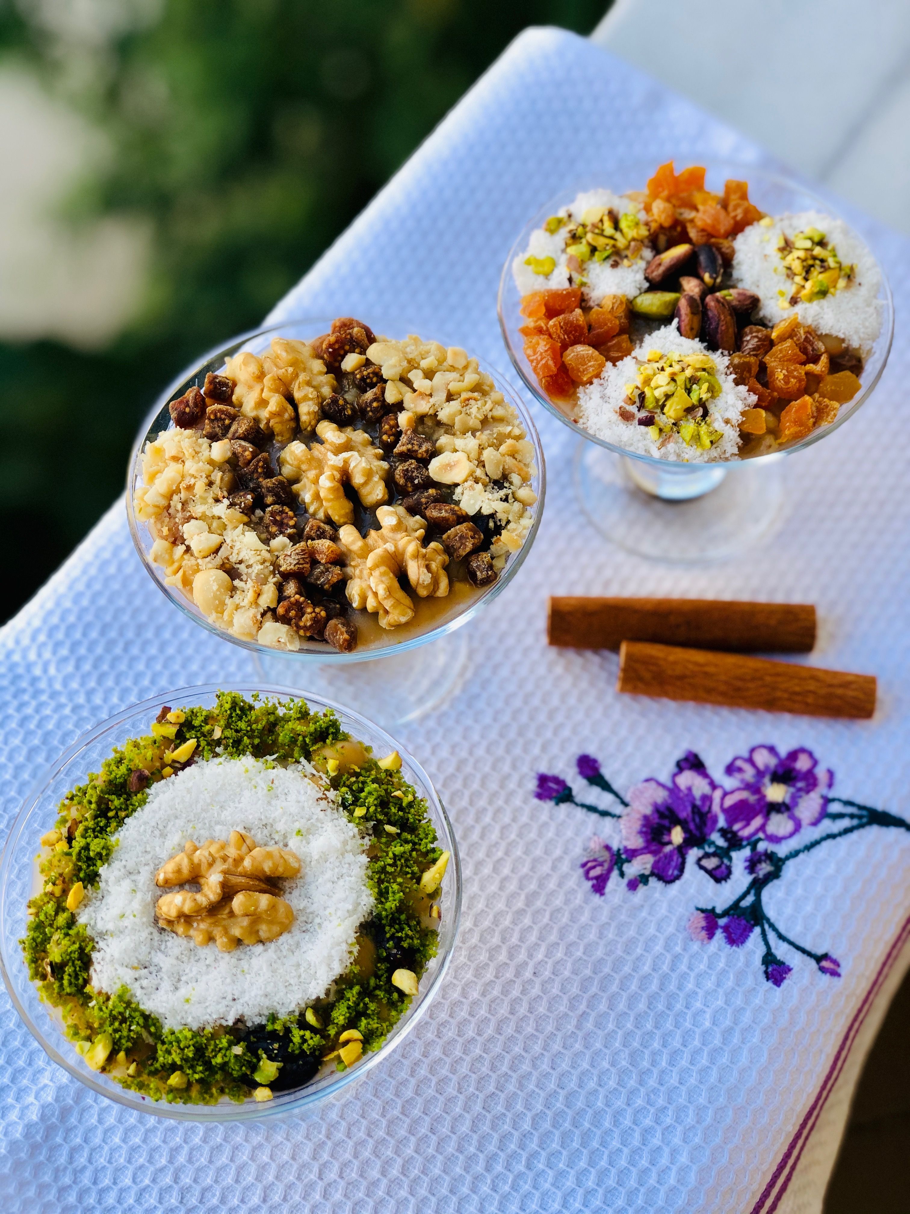 Three beautifully arranged fruit and nut parfaits topped with walnuts, raisins, and pistachios on a decorative napkin.