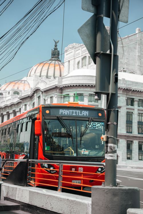 Free A red public transportation bus passing by the iconic Palacio de Bellas Artes in Mexico City. Stock Photo