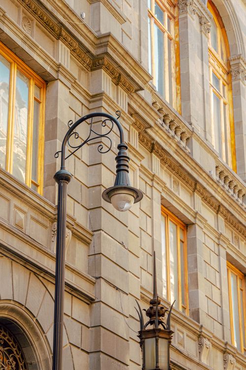 Free Charming vintage street lamp set against ornate classical building facade with decorative windows. Stock Photo