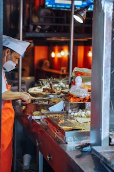 Chef preparing street food with vibrant ingredients at night market stall.