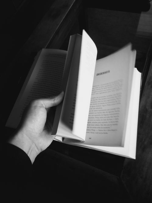 Free Monochrome photo of a person holding and turning pages in a book. Stock Photo