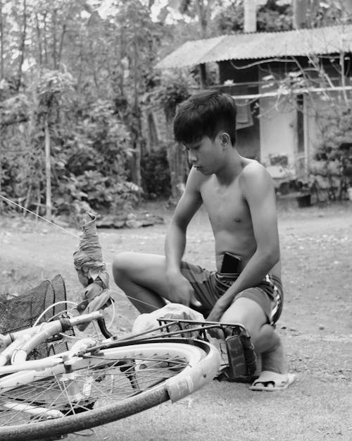 Kid Sitting Beside a Bicycle