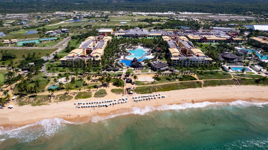 Vista aérea de um resort de luxo à beira-mar com piscina e vilas, ideal para lua de mel.