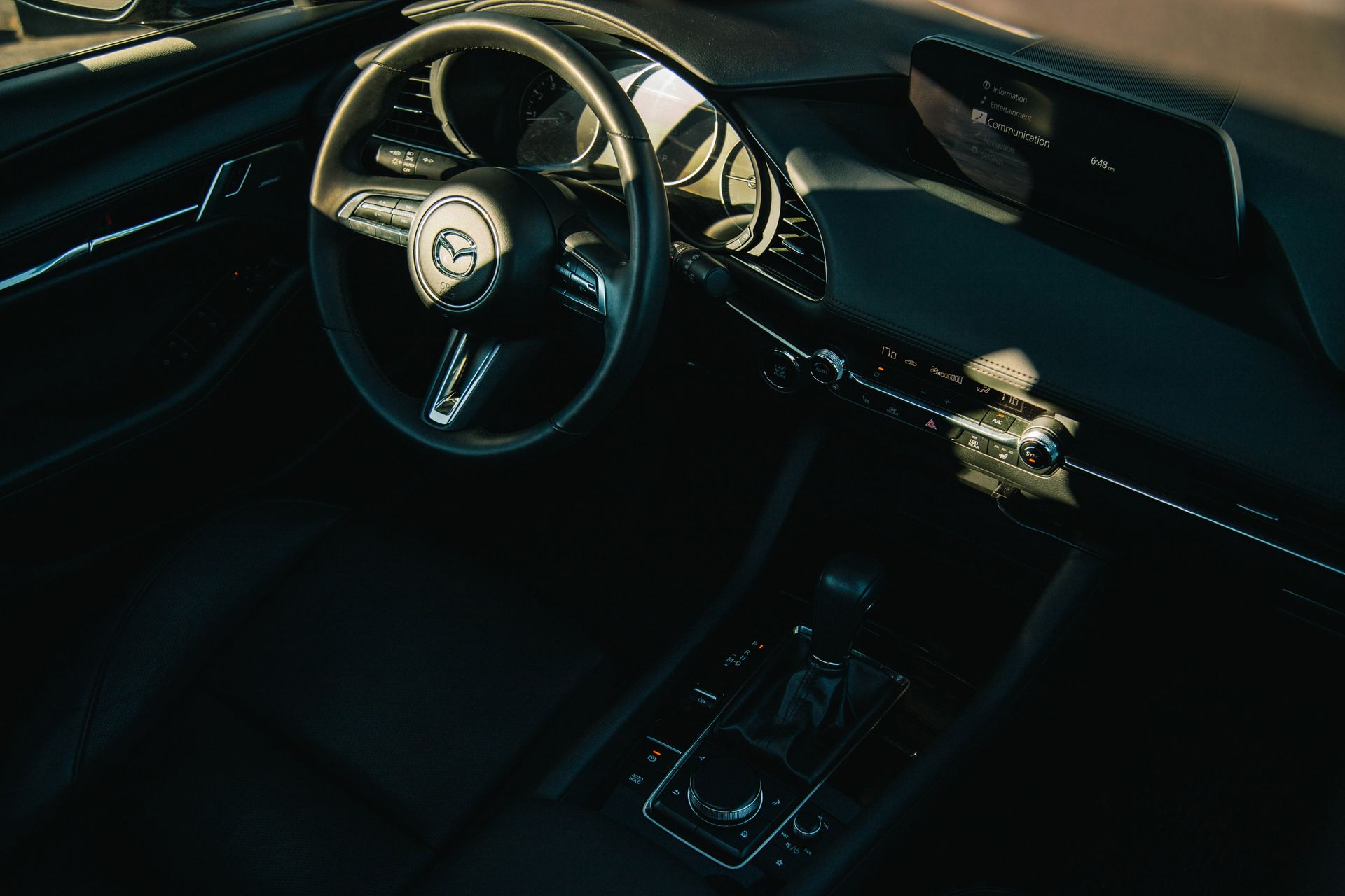 High angle view of Mazda car interior focusing on the dashboard and steering wheel.