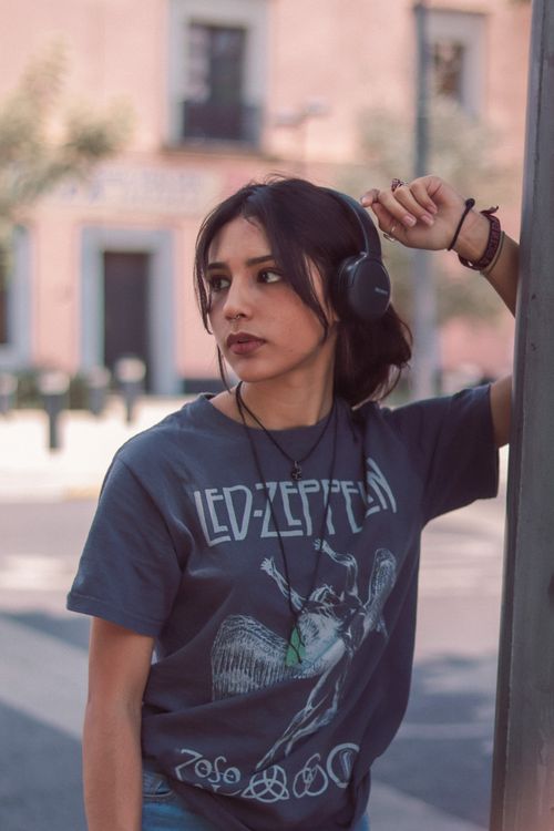 Free Casual young woman in a band t-shirt and headphones, enjoying music on a sunny day in Mexico City. Stock Photo