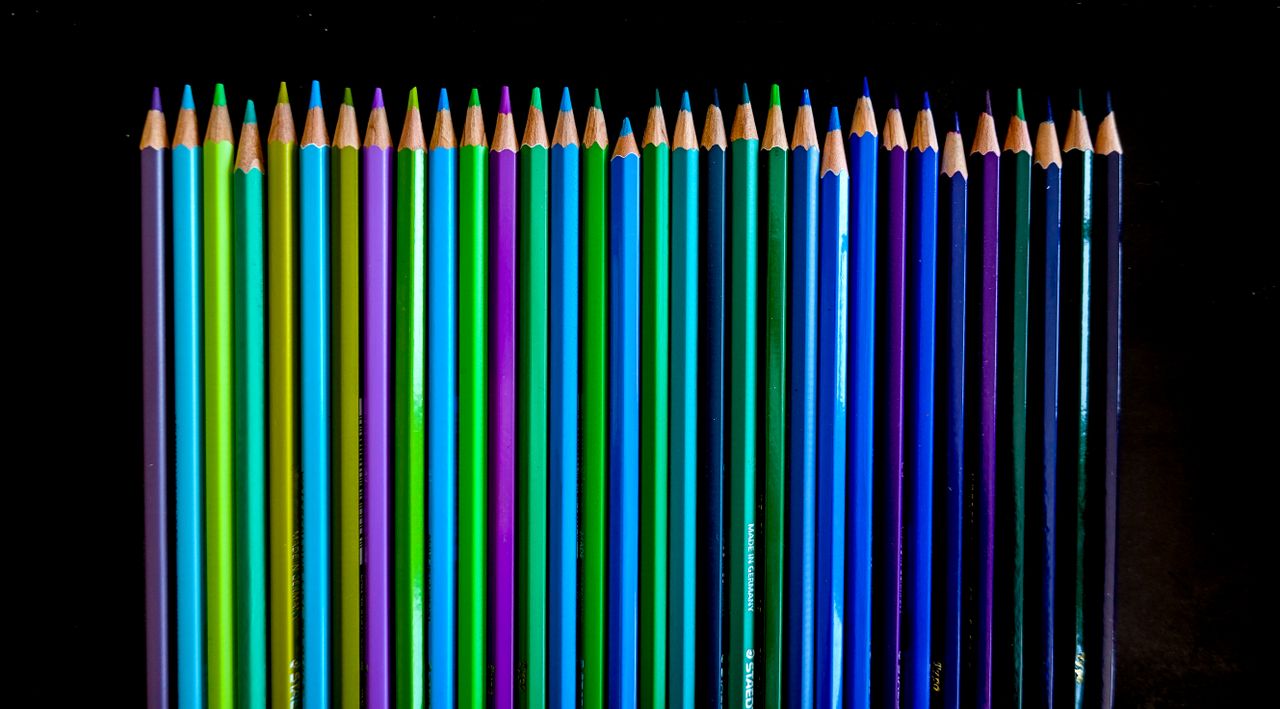 vibrant colored pencils arranged neatly on a black surface