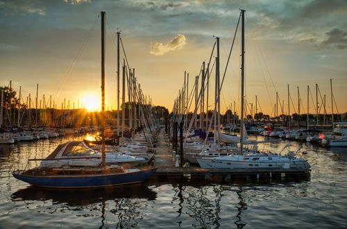 Free Tranquil sunset at a marina with sailboats docked along the water, creating a serene atmosphere. Stock Photo