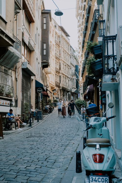Free Picturesque cobblestone street with people strolling amidst historic buildings. Stock Photo