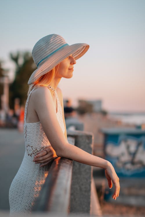 A Woman Wearing Sun Hat Leaning on Railing