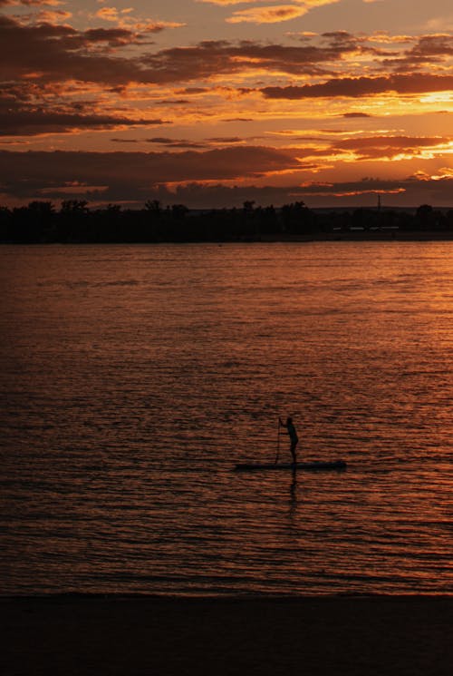 Silhouette of Person Standing on Paddle Board