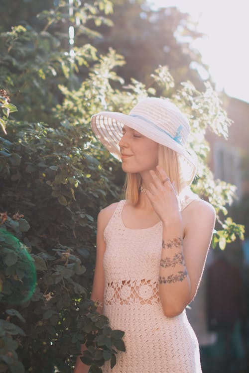 Woman in White Summer Hat Near Green Leaves