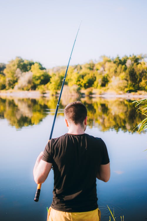 Person Holding Fishing Rod in Front of a River · Free Stock Photo