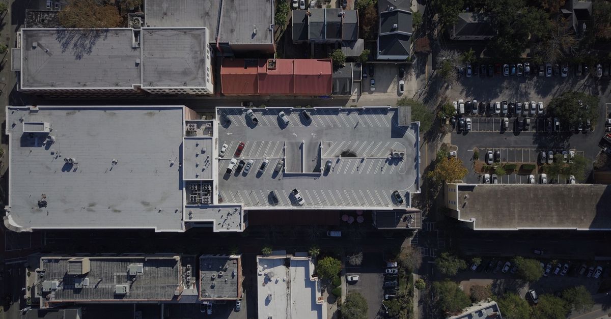 A detailed aerial view of a cityscape with buildings and a parking garage.