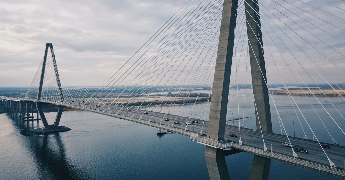 Drone shot highlighting the modern cable-stayed Arthur Ravenel Jr Bridge in South Carolina over tranquil waters.