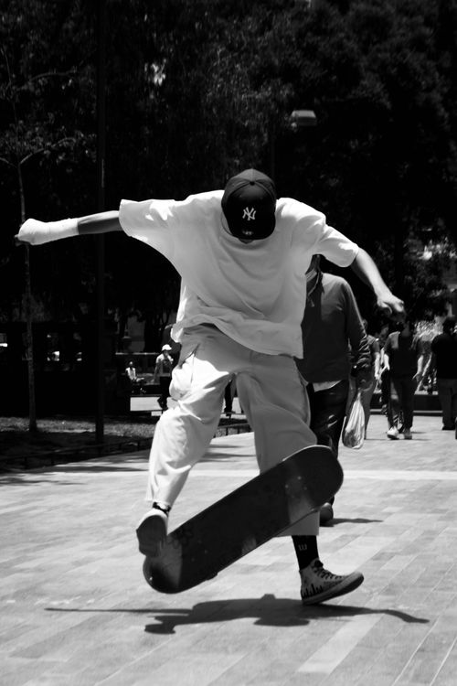 Free Black and white shot of a man skateboarding, caught mid-trick on a sunny day. Stock Photo