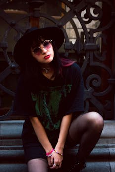 Fashionable woman in black attire posing outdoors with a gothic backdrop.