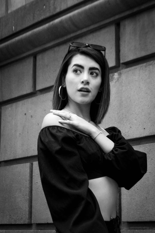 Free Stylish black and white portrait of a woman in urban setting wearing crop top and hoop earrings. Stock Photo