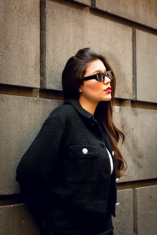 Free Fashionable woman in sunglasses leans against a concrete wall, exuding urban style. Stock Photo