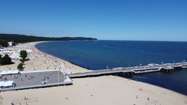 Explore the stunning aerial view of Sopot Pier and beach in Poland under clear blue skies.