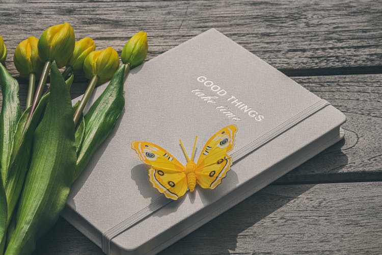 Yellow Tulips And Paper Butterfly On Notebook