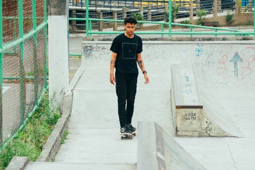 Free A young man wearing a black shirt skateboarding in an urban skatepark with graffiti and ramps. Stock Photo