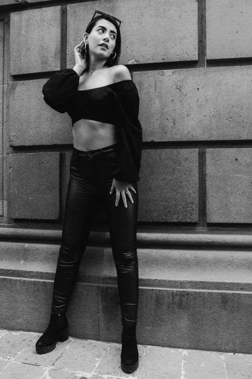 Free Black and white photo of a woman in urban fashion posing against a concrete wall. Stock Photo