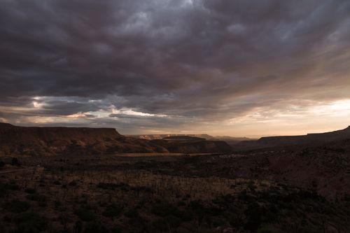 Free A breathtaking view of a desert landscape under dramatic clouds during sunset. Stock Photo