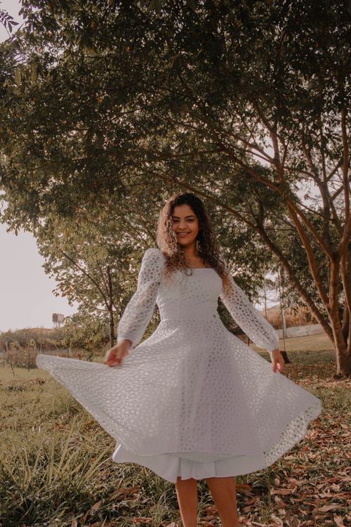 Free Young woman with curly hair enjoying nature in a white dress on a sunny day. Stock Photo