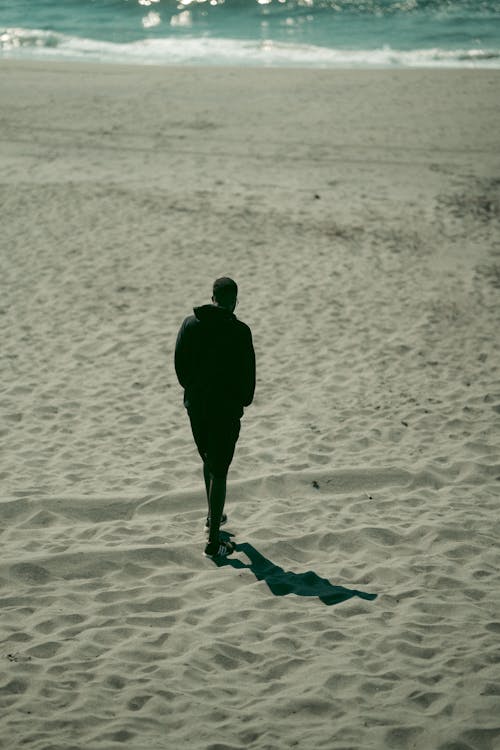 Photo of a Man Walking on Shore
