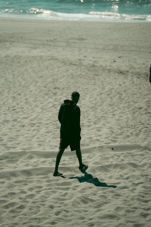 Photo of a Man Walking on Sand