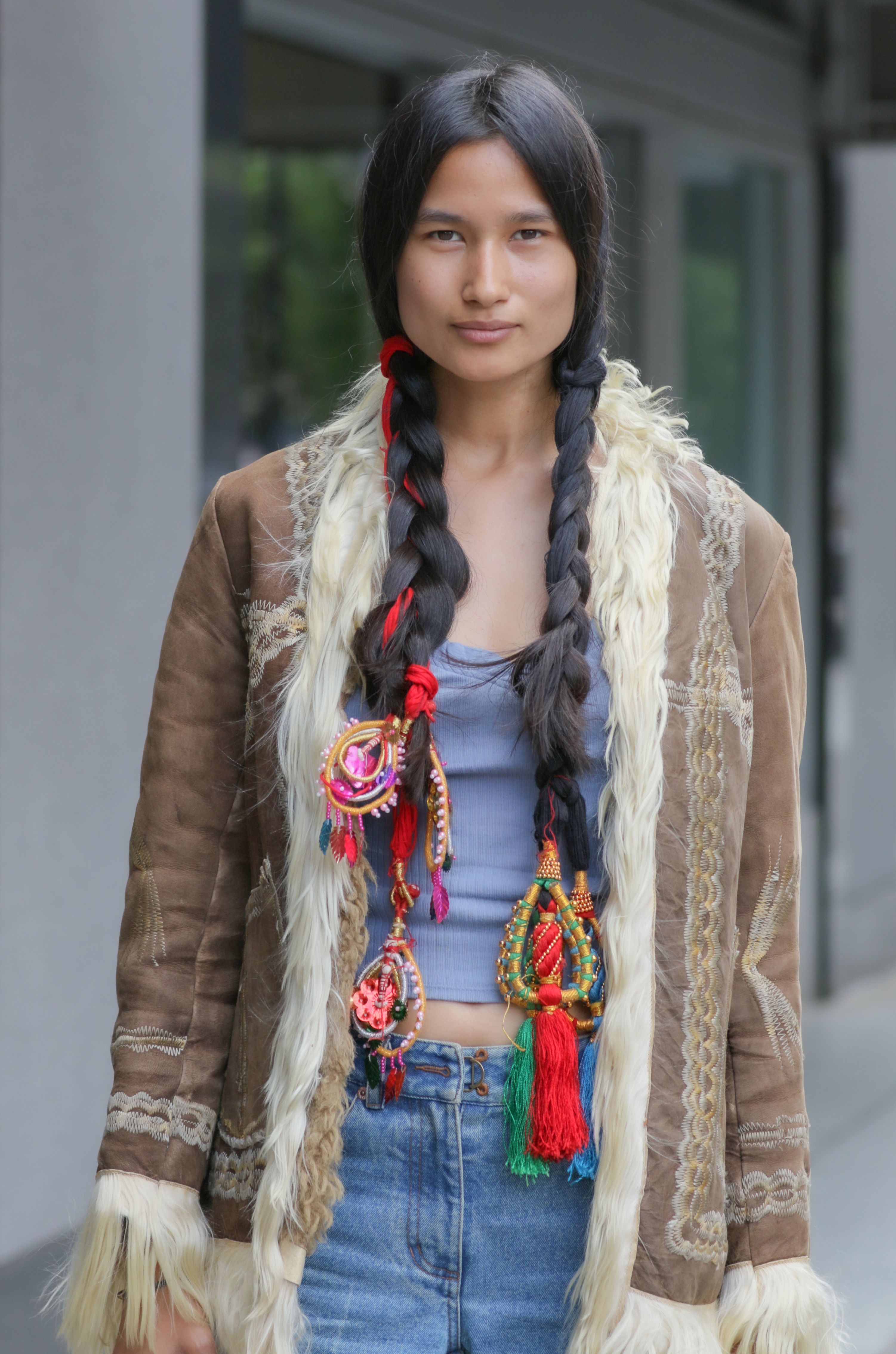 Portrait of a woman in bohemian attire, featuring intricate braided hair with vibrant accessories.