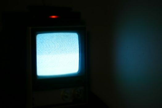 A vintage television displaying static in a dimly lit room, evoking nostalgia and retro vibes.