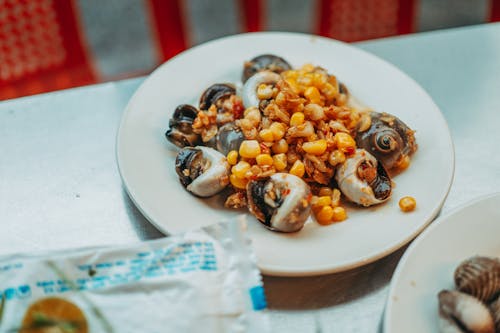 Foto de stock gratuita de un plato de escargots con granos de maíz y ajo frito