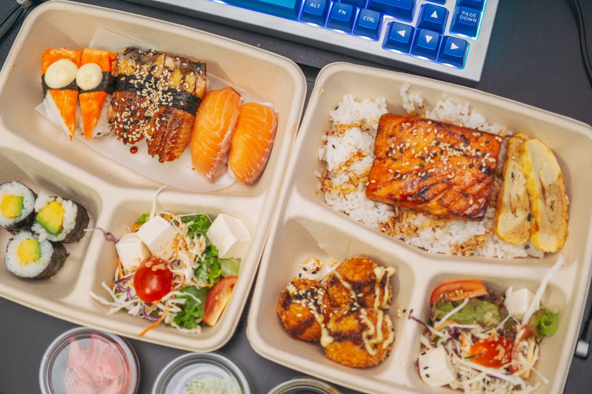 Flatlay of a Japanese bento box with sushi, sashimi, and colorful side dishes